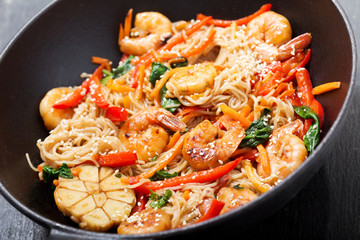Stir fried noodles with shrimps and vegetables in a wok