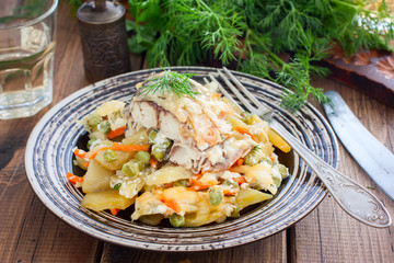 Baked mackerel with vegetables - potatoes, carrots, onions, green peas in a plate, selective focus