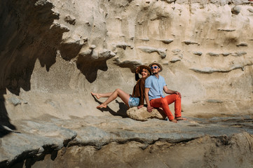 Fototapeta na wymiar Couple in sunglasses sitting on stone on the coastline