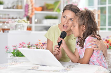 Portrait of mother and daughter singing karaoke with microphone together