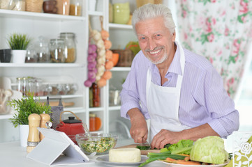Portrait of senior man preparing dinner in kitchen