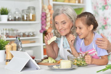 Portrait of senior woman with granddaughter preparing dinner