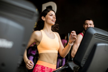 Fototapeta na wymiar Young couple running on treadmills in modern gym
