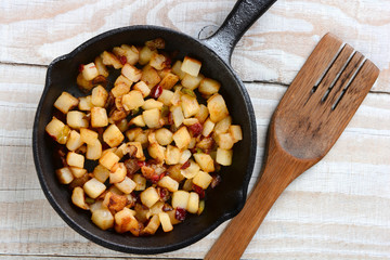 Fried breakfast potatoes in a skillet on a rustic wood table