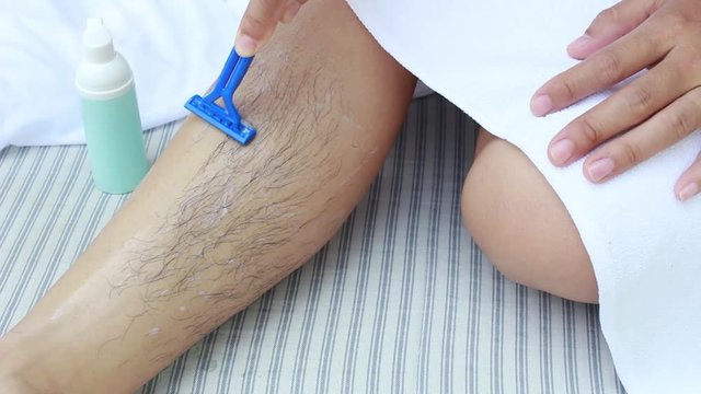 Close-up view of Asian woman shaving leg with razor. Body care and  Hair removal concept.