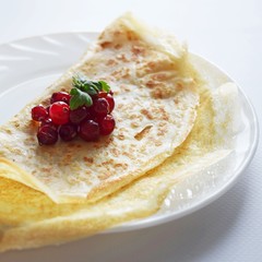 Delicious homemade pancakes with fresh berries on a white background.