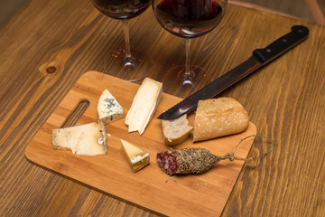 Red wine and assorted cheese plate with sausage