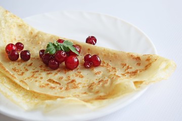Delicious homemade pancakes with fresh berries on a white background.