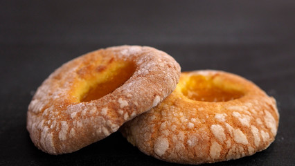 Two donuts with apricot jam on center a black background. Delicious fresh pastry will be an addition to tea or coffee in a friendly company.