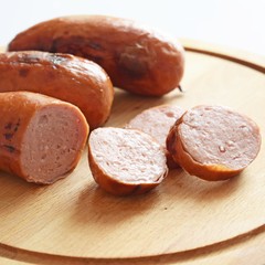Sausages fried on a fire on a wooden background.