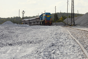 Railway locomotive with dump trucks for transportation of gravel. Quarry equipment. Mining industry.