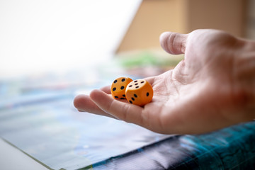 Hand throws two yellow dice on the playing field. Gaming moments in dynamics. Luck and excitement. Board games strategy