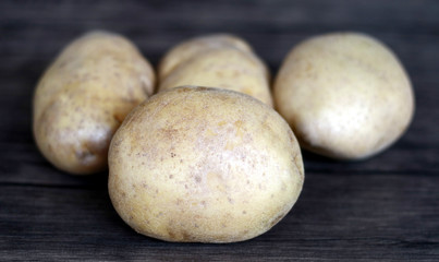 Yellow potatoes on wood background.