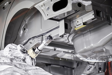 The robots in the car manufacturing plant are helping the car body to be glued at the seams.