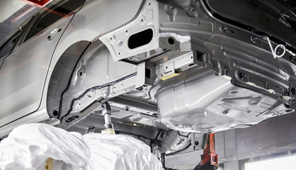 The robots in the car manufacturing plant are helping the car body to be glued at the seams.