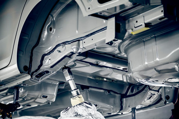 The robots in the car manufacturing plant are helping the car body to be glued at the seams.