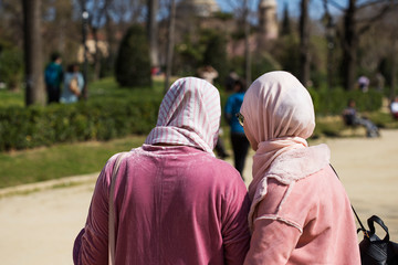 Two women wearing hijab in a public park, unrecognizable