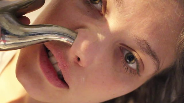 Close up portrait of a young adult woman cleaning her nose using metal neti pot. allergy / sinusitis / ayurveda / stuffy nose concept