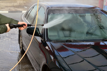 Contactless car wash self-service. Young man washing his car spring.