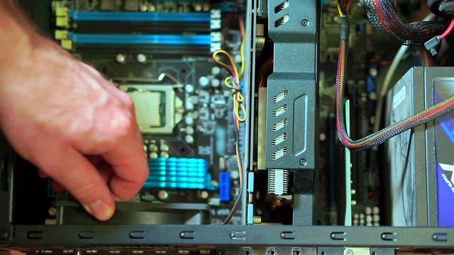 Close-up of male hand uninstalling fun in PC. Personal computer repair