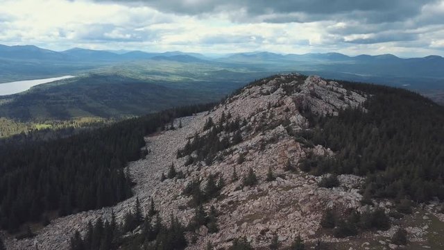 Aerial view of the top of mountains and forest under cloudy sky. Clip. Amazing Russian landscape
