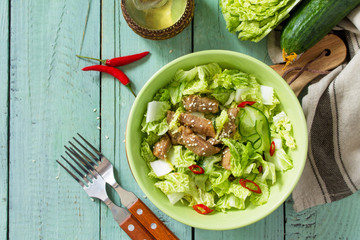 Diet menu. Healthy salad with Chinese cabbage, chicken, sesame and chili pepper on wooden table. Top view flat lay background. Copy space.