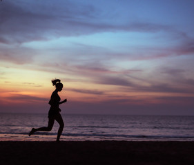Fototapeta premium Young, athletic lady jogging on a beach during the susnet