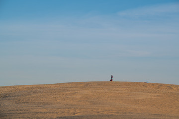 Fototapeta na wymiar People silhouetted walking on the top of a giant dune at Jockey's Ridge State Park in North Carolina