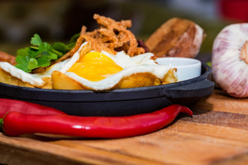 Nutricious meal with fried egg, sausages, beans, onion rings, chili pepper