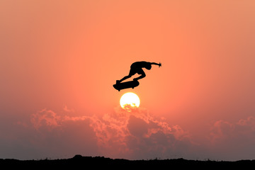Silhouette of skateboarder young teenager man on sunset background.