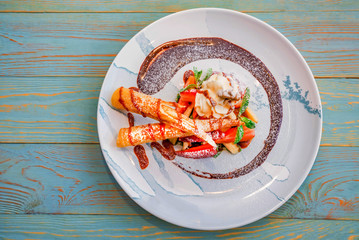 Top view delicious dessert with waffle rolls, ice cream and strawberries