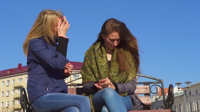 Two beautiful women gossip, a pretty young woman shares secret information with an astonished friend, sister, whispers in her ear, gossipers spread rumors, tell interesting funny news