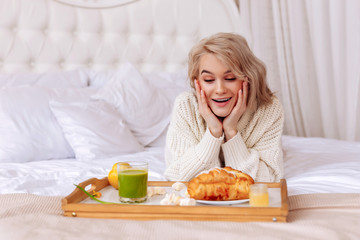 Obraz na płótnie Canvas Girlfriend feeling excited looking at tray with breakfast in bed