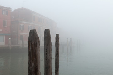 Canal on Murano island in the fog