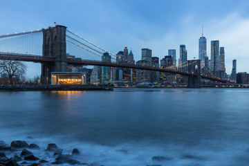 Naklejka na ściany i meble Brooklyn Bridge in Manhattan downtown with Cityscape on a foggy cloudy day at sunset New York USA