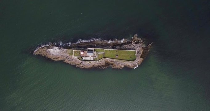 Drone shot descending on an island with a lighthouse