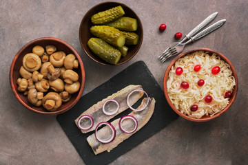 Traditional Russian appetizers, sauerkraut with cranberries, pickles, pickled champignon mushrooms, marinated herring. Top view, overhead