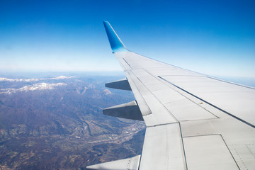 Photo from window of wing airplane flying over Alps mountains. Travel concept