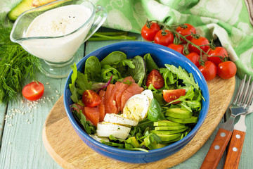 Diet menu, Vegan food. Healthy salad with arugula, Tomatoes, Salmon, Egg and Avocado on wooden table. Copy space.