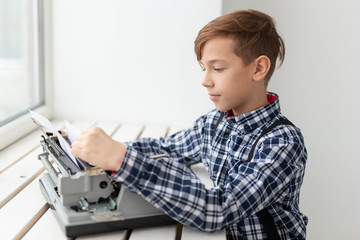 Fototapeta na wymiar World day of the writer concept - Boy changes the paper in the typewriter