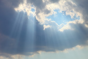 Ray of sun light shine through the gap among cloud with blue sky