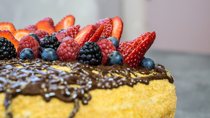 Hat cake, chocolate on top, juicy strawberries, raspberries and berries,side view