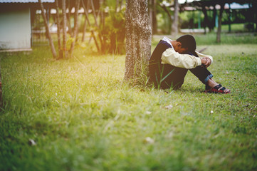 Picture of a young boy sitting sadly alone in the forest Depression concept