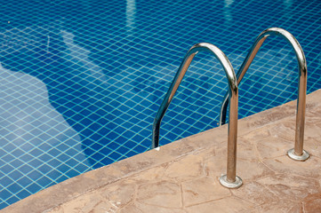Grab bars ladder in the blue swimming pool.