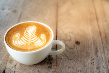 Close up caffe latte art coffee with flat milk in white ceramic coffee cup on wooden table in coffee shop cafe restaurant with morning sunlight. Concept for coffee lover or relaxation mood.