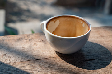 Empty coffee cup after drinking on vintage wooden table in nature decorative coffee shop cafe restaurant with blurred morning sunlight and nature backgrounds.