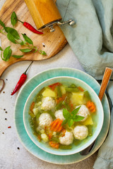 Healthy and tasty lunch. Baby food. Dietary Summer light vegetable soup with meatballs on stone table. Top view flat lay background.