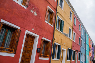 Coloured yellow and red house wall with windows on Murano Island in Venice Italy