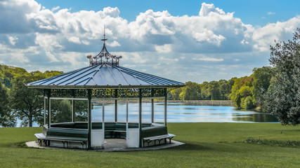 Victorian bandstand in Roundhay public park Leeds Yorkshire England with Waterloo Lake behind. - obrazy, fototapety, plakaty