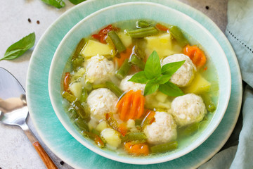 Healthy and tasty lunch. Baby food. Dietary Summer light vegetable soup with meatballs on stone table.